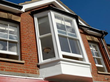 White bay window on a red brick building with two other white windows and black gutters at The Hideaway in Aldeburgh