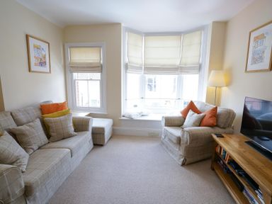A living room with a sofa armchair television and a wooden cabinet at The Hideaway Aldeburgh