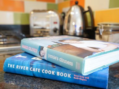 Two cookbooks stacked on a kitchen counter with a toaster kettle and a gas stove in the background at The Hideaway in Aldeburgh