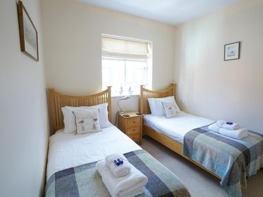 A bedroom with two single beds separated by a bedside table under a window at The Hideaway in Aldeburgh