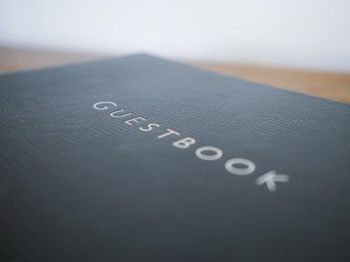 A close-up of a guestbook with a textured cover on a wooden surface at The Hideaway in Aldeburgh