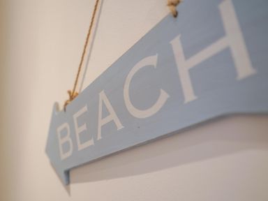 A close up of a blue wooden sign with the word beach hanging on a wall at The Hideaway in Aldeburgh
