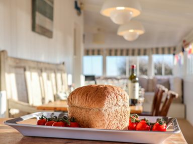 A loaf of bread and cherry tomatoes on a tray in a dining area at Valetta Thorpeness in Thorpeness