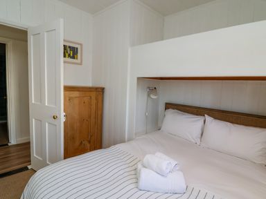 A bedroom with a made bed with white and striped bedding and towels on top at Valetta  Thorpeness