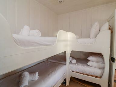 A small bedroom with white wooden bunk beds and rolled towels at Valetta Thorpeness in Thorpeness