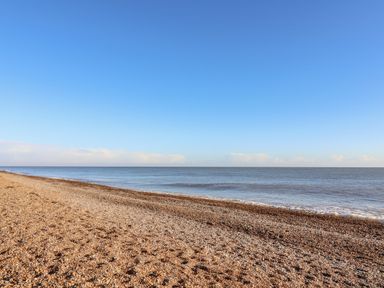 A pebble beach with calm sea and clear sky at Valetta Thorpeness in Thorpeness