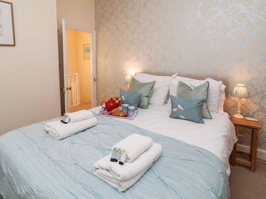 A bedroom with a bed with pillows towels and a tray with a teapot and cups at Winkle Cottage Aldeburgh