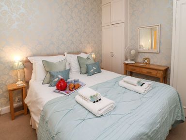 A bedroom with a double bed covered in blue bedding and white towels on top at Winkle Cottage Aldeburgh