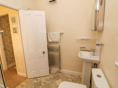 A bathroom with a sink toilet towel rack and mirror at Winkle Cottage Aldeburgh