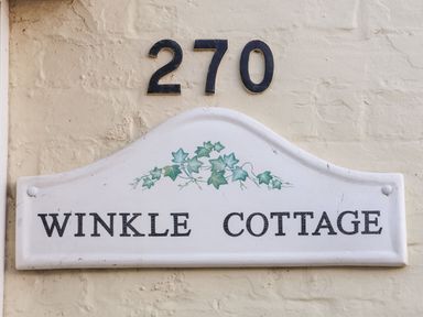 A house number 270 with a sign reading Winkle Cottage with a vine decoration on a wall at Winkle Cottage Aldeburgh