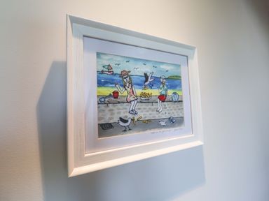 A framed artwork depicting people and seagulls at a beach at Seadrift Dunwich Near Westleton