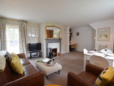 A living room with brown sofas a fireplace a dining table and chairs a television and a desk at Rookyards Spexhall Near Halesworth