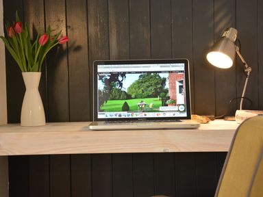 A desk with a laptop a vase with flowers a desk lamp and a book at Rookyards Spexhall Near Halesworth