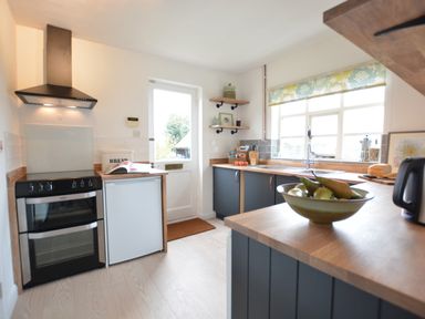 A kitchen with a stove fridge sink and countertop with a bowl of fruit at Rookyards Spexhall Near Halesworth