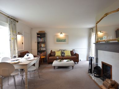 A living room with a dining table set with plates and glasses a leather sofa with cushions a bookcase a fireplace and a large mirror at Rookyards in Spexhall Near Halesworth