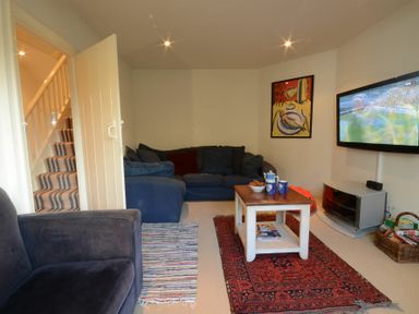 A sitting room with a blue sofa a coffee table and a television mounted on the wall at 2 The Bays Thorpeness