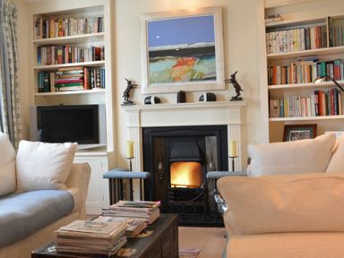 A living room with a fireplace between bookshelves and couches at 2 The Bays Thorpeness