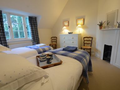 A bedroom with two single beds a white dresser two chairs and a small fireplace at 2 The Bays Thorpeness