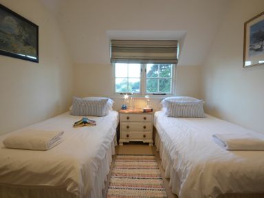 A bedroom with two single beds separated by a nightstand under a window at 2 The Bays Thorpeness