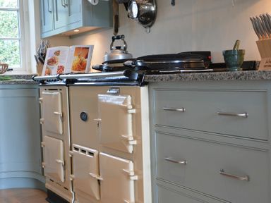 A kitchen with a cream-colored stove kettle cookbook knives and a green mortar and pestle at 2 The Bays Thorpeness