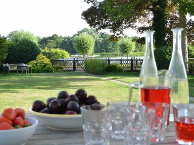 A garden with a table holding bowls of fruit and glasses of red drink at 2 The Bays Thorpeness