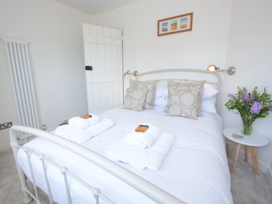 A bedroom with a white metal bed frame decorated with patterned pillows and folded towels on a bed at 4 The Dunes Thorpeness