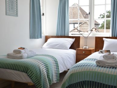 A bedroom with two single beds with patterned blankets and white pillows at 4 The Dunes Thorpeness