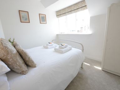 A bedroom with a bed folded towels and framed pictures on the wall at 4 The Dunes Thorpeness