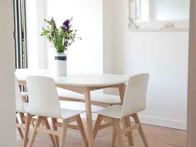 A dining area with a wooden table and chairs and a vase with flowers on the table at 4 The Dunes Thorpeness