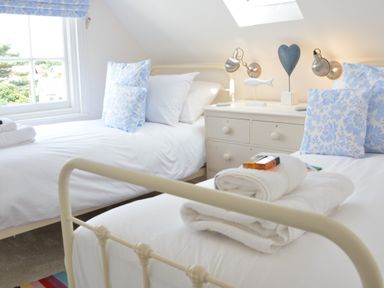 A bedroom with two single beds white drawers between them and blue patterned pillows at 4 The Dunes Thorpeness