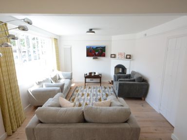 A living room with three sofas a rug a wall-mounted TV and a small table at 4 The Dunes in Thorpeness
