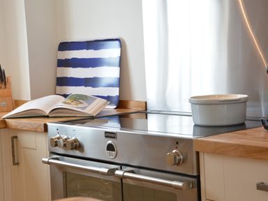 A kitchen stove with a white pot a striped tray and an open cookbook at 4 The Dunes Thorpeness