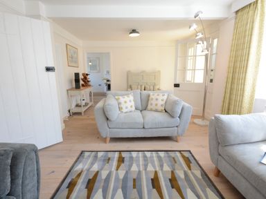A living room with two gray sofas a patterned rug wooden floor a floor lamp and a console table at 4 The Dunes Thorpeness