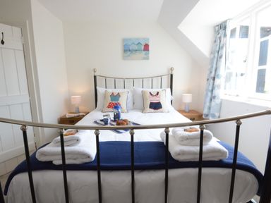 A bedroom with a metal bed frame two bedside tables with lamps and folded towels on the bed at 4 The Dunes Thorpeness