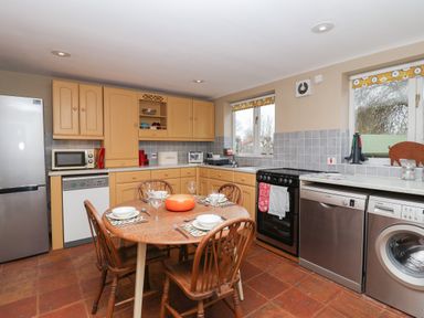 A kitchen with dining table and four chairs dishwasher washing machine and windows at 1 The Old Coach House Huntingfield Near Laxfield