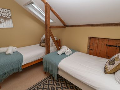 A bedroom with two single beds separated by a wooden beam and a skylight at 1 The Old Coach House Huntingfield Near Laxfield