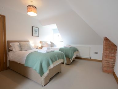 A bedroom with two single beds with green blankets and pillows at Ash Tree Cottage in Aldringham