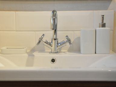 A close up of a bathroom sink with a chrome faucet and soap dispenser at Ash Tree Cottage Aldringham