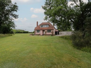A detached house with a tiled roof and grass lawn surrounded by trees at Ash Tree Cottage Aldringham