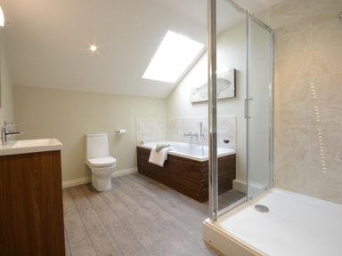 A bathroom with a toilet sink shower and bathtub under a skylight at King George Penthouse in Aldeburgh