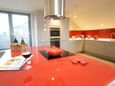 A kitchen with a red countertop island and a red pot at King George Penthouse in Aldeburgh