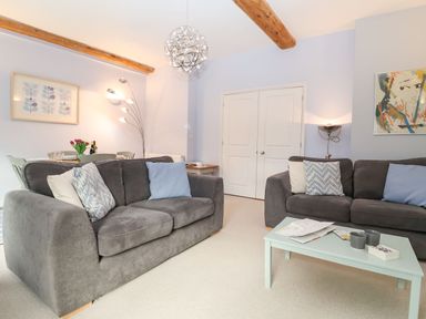 A living room with two grey sofas a coffee table and a dining area at Saffron Blythview in Blythburgh near Southwold
