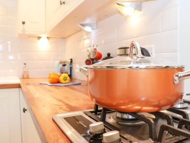 A kitchen countertop with a pot on a gas stove and bell peppers on a cutting board at Saffron Blythview in Blythburgh near Southwold