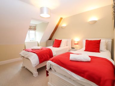 A bedroom with two single beds with red blankets and pillows at Saffron Blythview in Blythburgh near Southwold