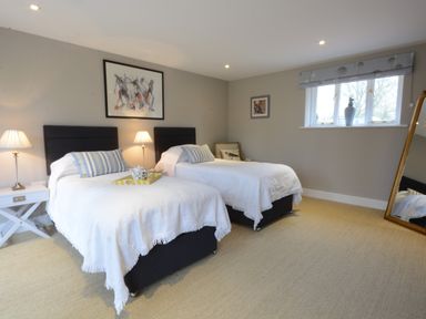 A bedroom with two single beds lamps a window and a standing mirror at Bird Cottage Burgh Near Grundisburgh