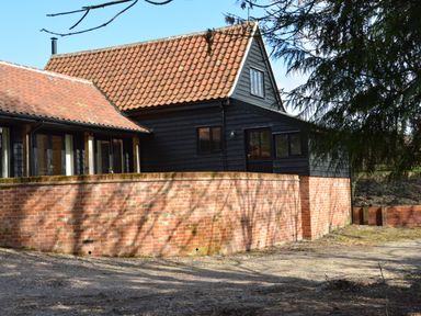 A building with a tiled roof black wooden walls and a brick wall in front at Bird Cottage Burgh Near Grundisburgh