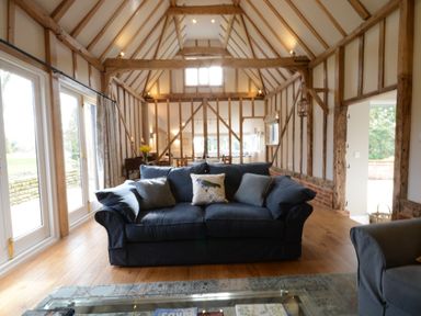 Living room with a blue sofa and wooden beams at Bird Cottage Burgh Near Grundisburgh
