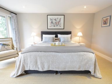 A bedroom with a bed a chair two lamps and framed artwork at Bird Cottage Burgh Near Grundisburgh