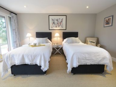 A bedroom with two single beds a nightstand with lamps and framed art on the walls at Bird Cottage Burgh Near Grundisburgh