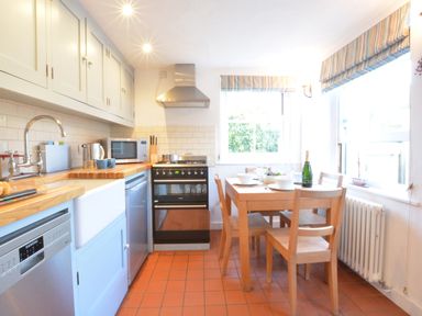 A kitchen with wooden countertops dining table with chairs and kitchen appliances at 1 South Cottages in Thorpeness